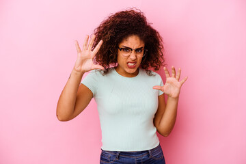 Young african american woman isolated on pink background showing claws imitating a cat, aggressive gesture.