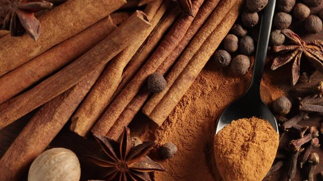 close up of various spices rotating on wooden table top view
