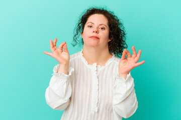 Woman with Down syndrome isolated relaxes after hard working day, she is performing yoga.