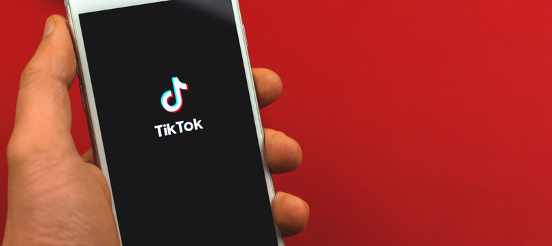 Kharkov, Ukraine - February 22, 2021: Tiktok app close up on Apple iPhone screen, studio shot on red background, banner and copy space