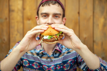 Guy in a stylish Shirt enjoying a Burger on a Patio Deck