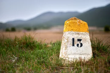 Foto op Plexiglas milestone or milepost sign on a rural road with hills in the bac © GRAFISPHOS