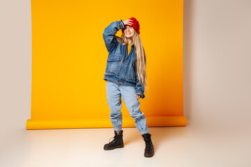 Cheerful trendy woman in denim outfit and hat having fun in studio