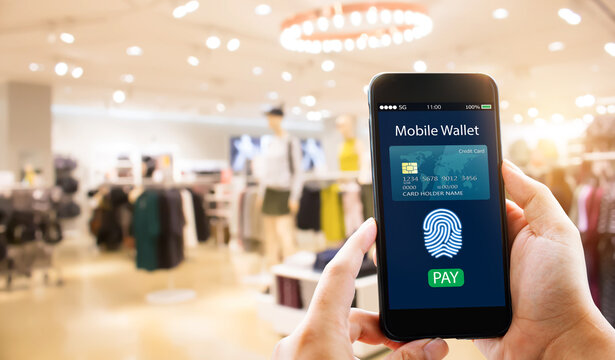 Digital Mobile Wallet Concept.Hands Holding Mobile Phone On Blurred Fashion Store As Background