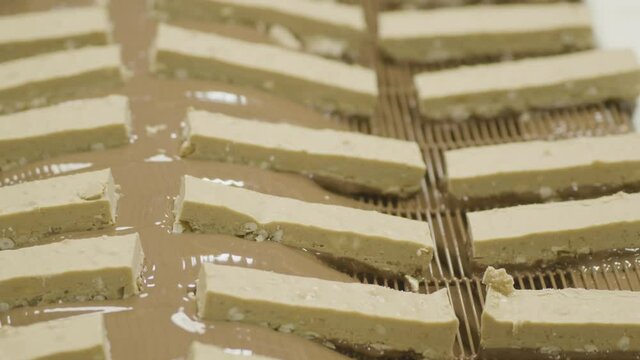 4K White Chocolate and Prezel Bars Are Dipped in Chocolate Along A Conveyor Belt