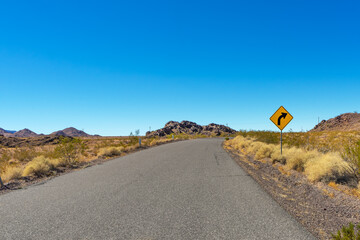 Road in the Mojave Desert with a caution sign
