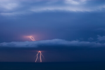 Double lightning strikes the sea through a cloud