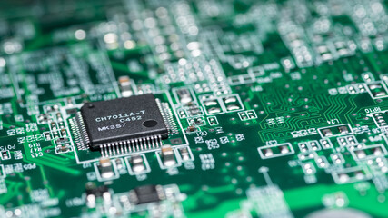 Fragment of a green computer printed circuit board with selective focus on an abstract microchip,...