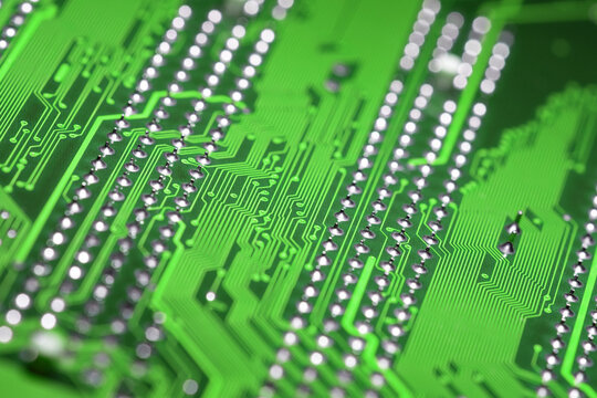 Abstract macro view of green printed circuit board with shiny pins blurred background, diagonal composition