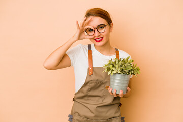 Young skinny arab gardener woman excited keeping ok gesture on eye.