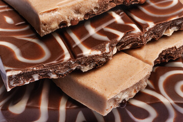 Slices of milk and dark chocolate with crispy balls close-up, sweet cocoa dessert.