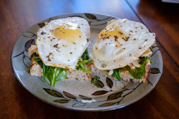 Two fried eggs over a bed of greens on slices of sourdough bread