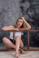 Naklejka premium blonde girl in shorts sitting on the floor