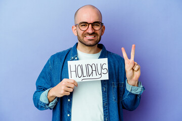 Young caucasian bald man holding a holidays placard isolated on blue background showing number two with fingers.