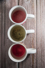 Tres tazas ya vacías con posos de diferentes tipos de té, sobre una mesa de madera.