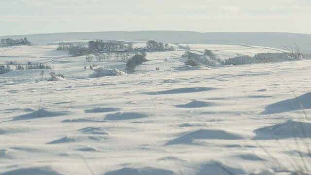 Wind blowing drifts across a snow covered landscape deep in the North of England countryside