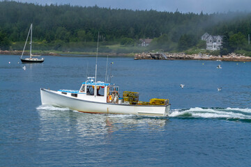 Fototapeta na wymiar A Lobster boat with traps heading out to check his traps.
