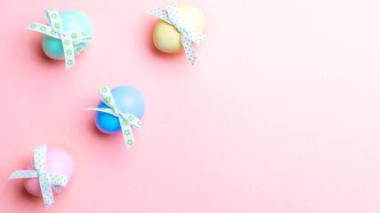 Easter holiday. Colourful egg with tape ribbon on pastel pink background in Happy Easter decoration. Spring holiday top view with copy space.