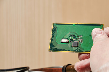 Worker keep pcb with a chip in the hand over the laboratory table. Manufacturing and nanotechnology...