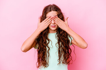 Little caucasian girl isolated on pink background afraid covering eyes with hands.