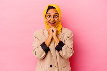 Young business muslim woman isolated on pink background praying for luck, amazed and opening mouth looking to front.