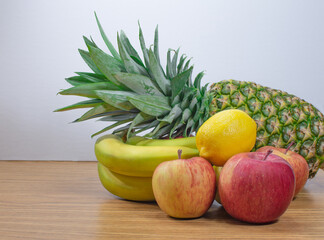 a pile of fruit laid horizontally on a wooden table with white background and blank print space