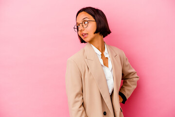 Young business mixed race woman isolated on pink background laughs happily and has fun keeping...