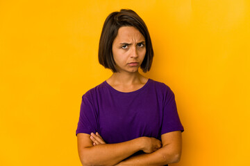 Obraz premium Young hispanic woman isolated on yellow frowning face in displeasure, keeps arms folded.