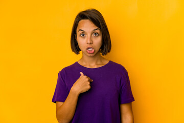 Young hispanic woman isolated on yellow surprised pointing with finger, smiling broadly.