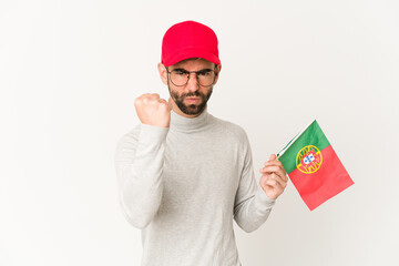 Young hispanic mixed race woman holding a portugal flag showing fist to camera, aggressive facial expression.