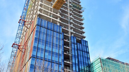 View of a skyscraper under construction. Modern architecture background. Building a high-rise building,  the concept of real estate construction. 