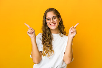 Young caucasian woman pointing to different copy spaces, choosing one of them, showing with finger.