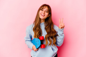 Young skater woman isolated on pink background showing number two with fingers.