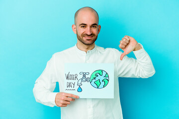 Young caucasian bald man celebrating world water day isolated on blue background showing a dislike gesture, thumbs down. Disagreement concept.