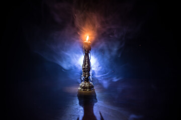 Single burning candle. Light of flame and flowing candle wax, dark background