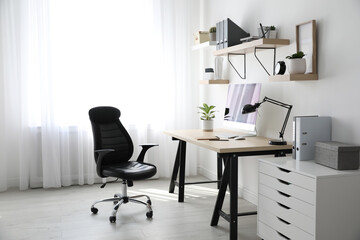 Comfortable office chair near table with modern computer