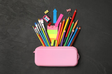 Fototapeta premium Flat lay composition with different school stationery on black stone table. Back to school