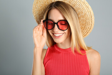 Beautiful woman in stylish sunglasses on grey background