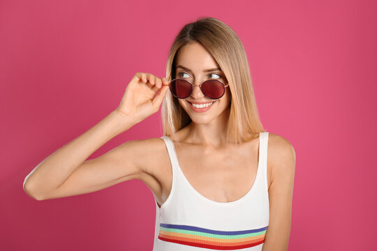 Beautiful woman in stylish sunglasses on pink background