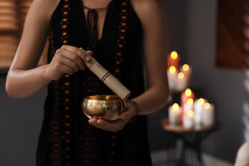 Healer using singing bowl in dark room, closeup