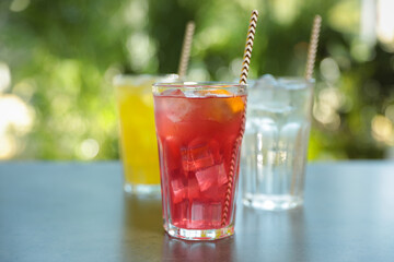 Delicious refreshing drinks in glasses on grey table outdoors