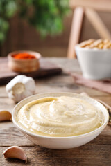 Delicious creamy hummus in dish on wooden table