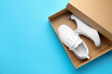 Stylish sport shoes in box on light blue background, top view. Space for text