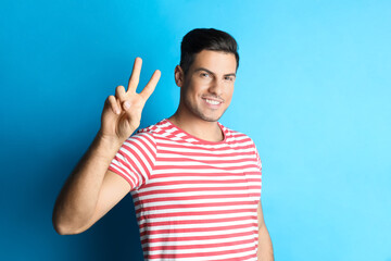 Man showing number two with his hand on light blue background