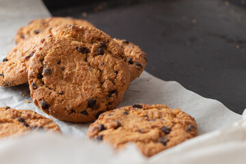 Crispy oatmeal cookies with chocolate on baking paper. Homemade cakes.