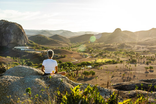 Mulher meditando em cima da montanha ao por do sol