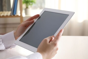 Woman with modern tablet at table indoors, closeup
