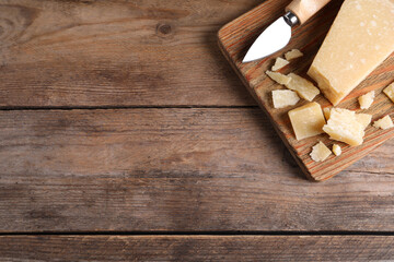 Parmesan cheese with knife on wooden table, top view. Space for text