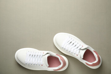 Stylish white sneakers on grey background, top view. Space for text