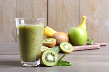 Delicious kiwi smoothie and fresh fruits on wooden table. Space for text